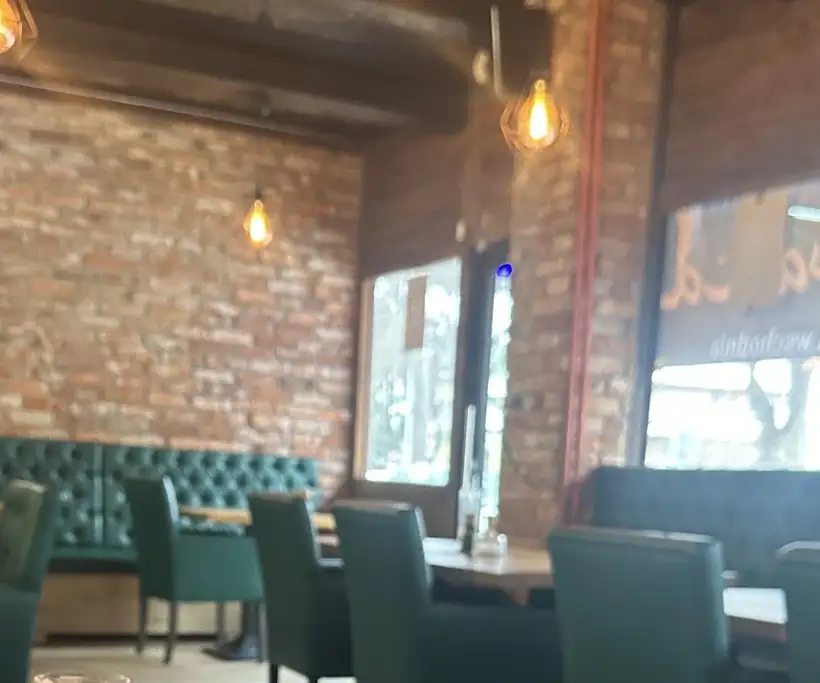 Sala restauracji z ceglaną ścianą i zielonymi kanapami
