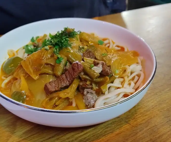 Lagman z wołowiną, papryką i fasolką w białej misce